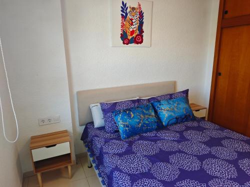 a bedroom with a purple bed and a picture on the wall at Oasis en la playa de Albir Apartamento in Albir
