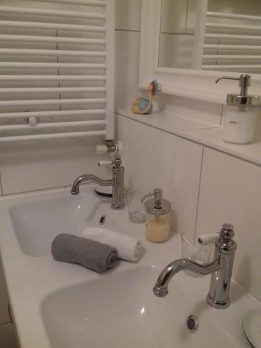 a bathroom sink with two faucets and a towel at Ferienwohnung Wiesmühlstrasse in Henndorf am Wallersee