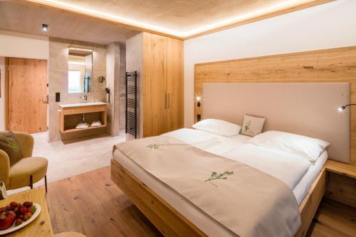 a bedroom with a large bed and a bathroom at Naturhotel Alpenrose in Millstatt