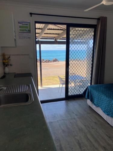 a kitchen with a sliding glass door with a view of the ocean at Absolute Oceanfront Tourist Park in Bargara