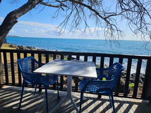 a table and two chairs on a deck with the ocean at Absolute Oceanfront Tourist Park in Bargara