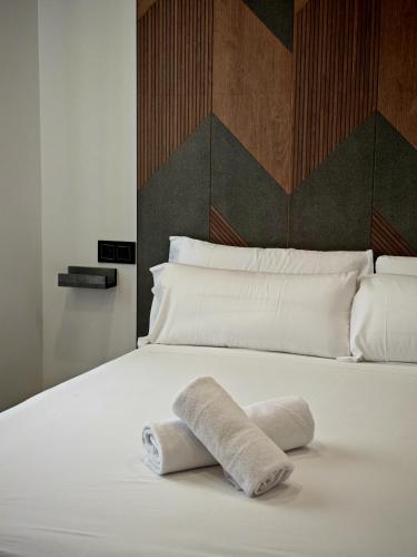 a white bed with two rolled towels on it at La Banda Suites in Seville