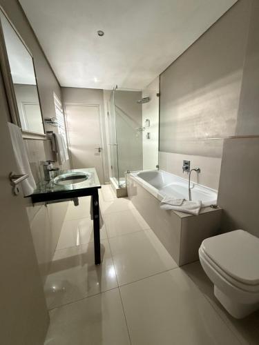 a bathroom with a tub and a toilet and a sink at Infinity Beach view in Cape Town