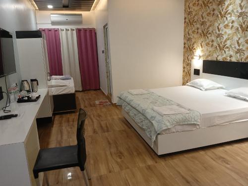 a bedroom with a bed and a desk with a chair at Hotel Buddha Park near Sarnath, Varanasi in Varanasi