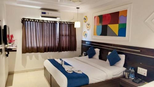 a bedroom with a large bed with blue pillows at Hotel Park Inn Shirdi - 100m From the Sai Temple in Shirdi