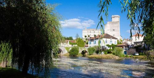 a river in a town with a bridge and a castle at Duplex 4 personnes avec jardin in Brantôme