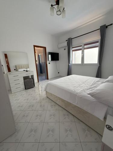 a white bedroom with a large bed and a dresser at Murati Lake View Hotel in Tirana