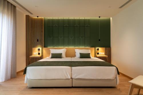 a bedroom with a large bed with a green headboard at Hotel do Alboi in Aveiro