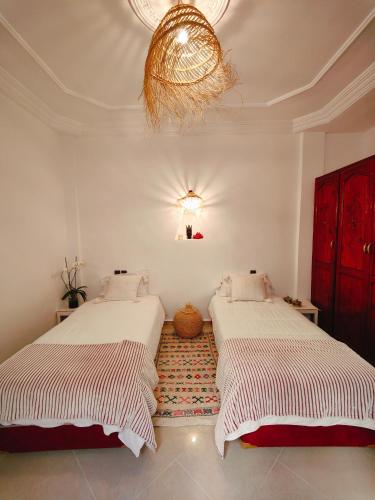 a bedroom with two beds and a chandelier at Riad Noor in Agadir