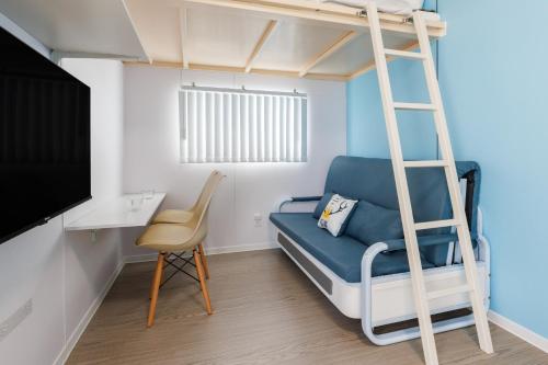 a room with a bunk bed with a blue couch and a chair at 最大18名OK 南城市 百名の大型貸別荘 BBQ ビーチ近くでグループ滞在に最適 Seaside House Ichika in Nanjo