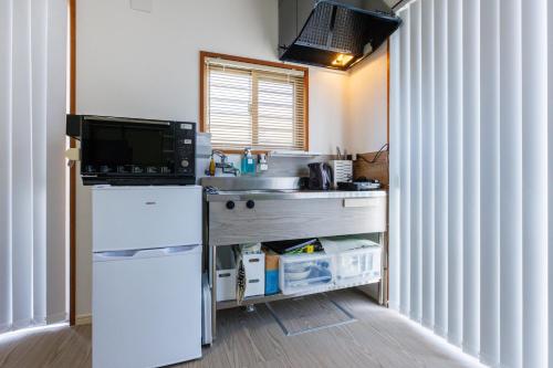 a small kitchen with a sink and a refrigerator at 最大18名OK 南城市 百名の大型貸別荘 BBQ ビーチ近くでグループ滞在に最適 Seaside House Ichika in Nanjo