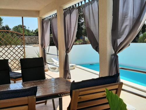 a dining room with a table and chairs and a pool at SEA YA - two apartments house with heated pool - 150m from beach in Zaglavice
