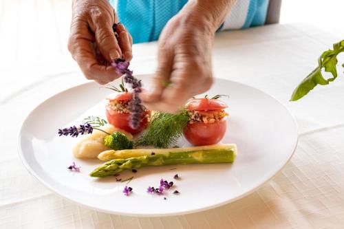 a person adding flowers to a plate of food at Naturhotel Alpenrose in Millstatt
