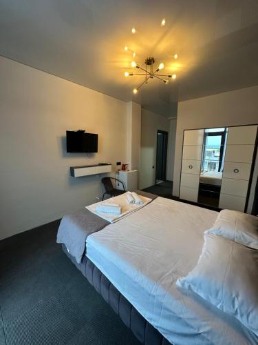 a bedroom with a large white bed and a television at Hotel black sea in K'obulet'i