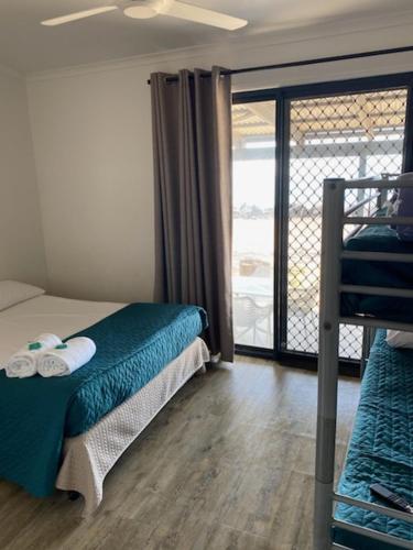 a bedroom with a bed and a balcony at Absolute Oceanfront Tourist Park in Bargara