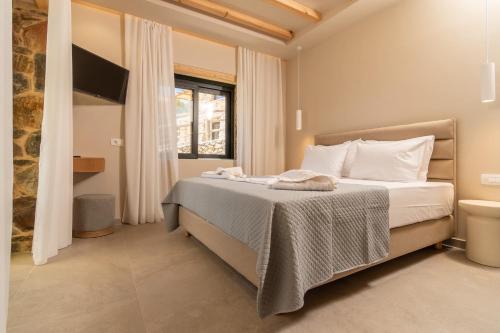 a bedroom with a bed with white sheets and a window at Aoria Villas in Palaiochóra