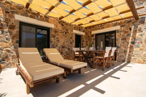 a patio with lounge chairs and a table with a dining room at Aoria Villas in Palaiochóra