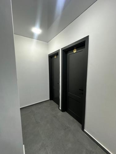 two black doors in a white room with a tile floor at Hotel black sea in K'obulet'i