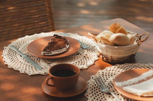a table with a cup of coffee and a basket of bread at Pousada Casa Mandacaru Noronha in Fernando de Noronha