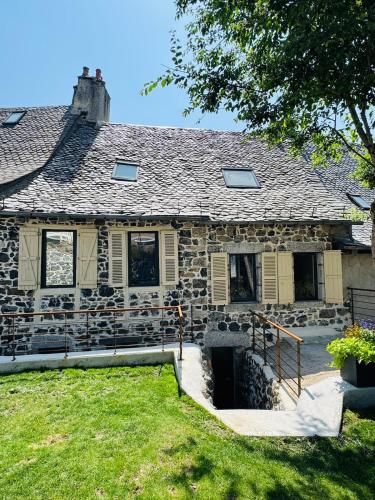 an old stone house with a yard in front of it at Maison Ombre du Clocher in Laguiole