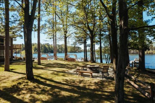 a picnic area with benches and a picnic table next to a lake at TC Lake Stay-Pontoon & SUP Rentals - Sleeps 4! in Traverse City