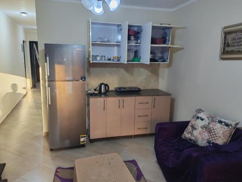 eine Küche mit einem Kühlschrank aus Edelstahl und einem Sofa in der Unterkunft منتجع اكوا ڤيو الساحل الشمالي in El Qasaba esh Sharqīya