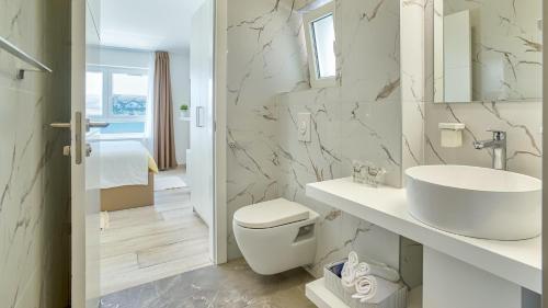 ein weißes Badezimmer mit Waschbecken und Toilette in der Unterkunft Vila Romana by Resort Čulina in Metajna
