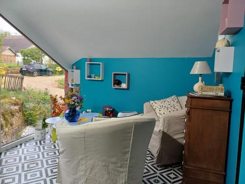 a room with a couch and a table and a blue wall at Le pigeonnier des cyclo courgettes in Fleurey