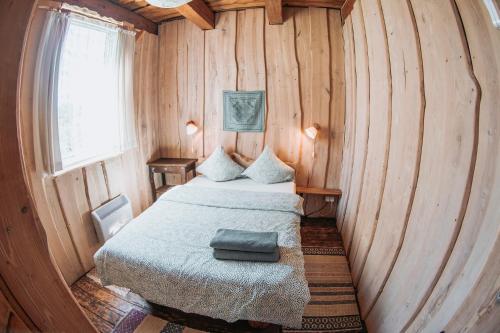 a small room with a bed in a wooden wall at Sunny Nights Homestead Rustic House in Gataučiai