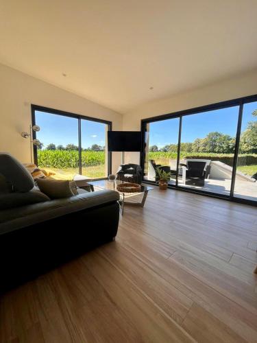 - un salon avec un canapé et de grandes fenêtres dans l'établissement Maison bretonne rénovée à 20 min des plages, parking privé, à Grand-Champ