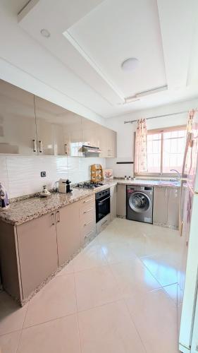 a large kitchen with white cabinets and a dishwasher at Appartement la perle bleu in Agadir