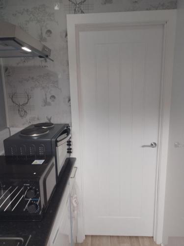 a door leading into a kitchen with a microwave at Studio Twenty One in Whitburn