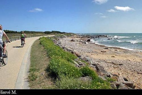 two people riding bikes on a path near the beach at Appartement l'Archipel - Vue mer exceptionnelle et bassins aquatiques du 29 avril au 15 sept in Talmont
