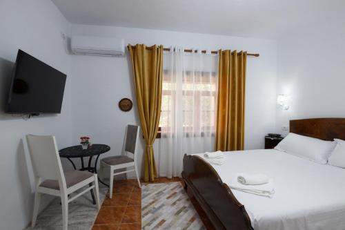 a bedroom with a bed and a table and a television at Kashah Residence in Gjirokastër