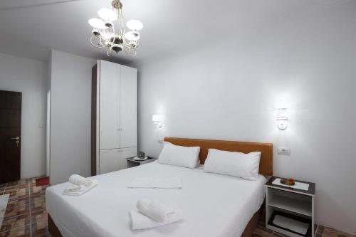a bedroom with a large white bed with a chandelier at Kashah Residence in Gjirokastër