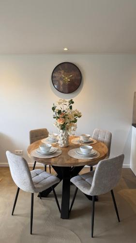 a dining room table with chairs and a clock on the wall at De Kajuit in Westkapelle