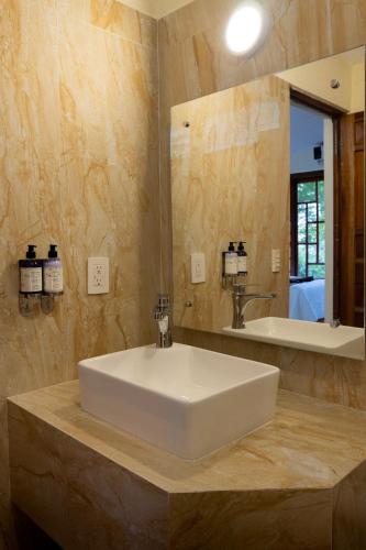 a bathroom with a white sink and a mirror at Hotel Nututun Palenque in Palenque