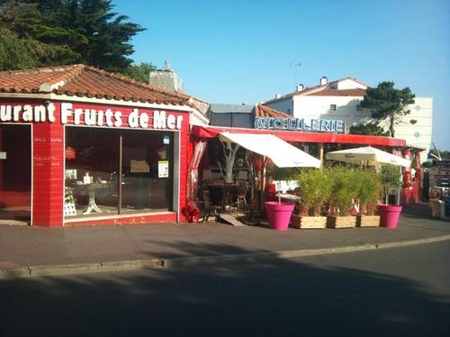 a red building with a restaurant on a street at Appartement l'Archipel - Vue mer exceptionnelle et bassins aquatiques du 29 avril au 15 sept in Talmont
