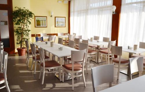 una sala da pranzo con tavoli e sedie bianchi di Hotel Midi a Lido di Jesolo