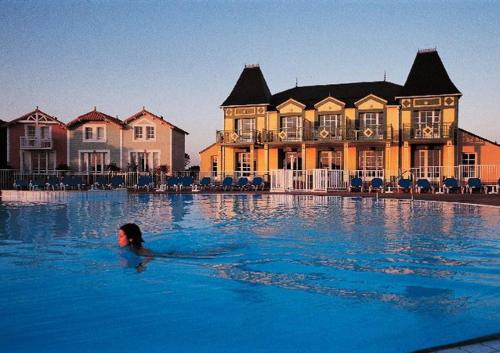 a woman swimming in a pool in front of a house at Appartement l'Archipel - Vue mer exceptionnelle et bassins aquatiques du 29 avril au 15 sept in Talmont