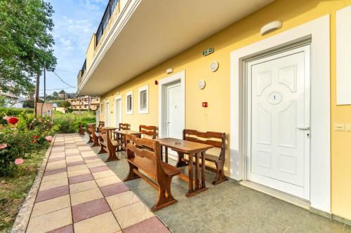 a patio with wooden benches and a white door at Kosmos Hotel in Agios Stefanos