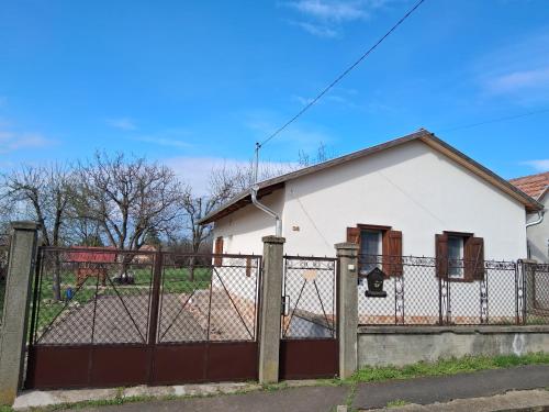 a white house with a fence in front of it at GABE Vendègház in Gyöngyöstarján