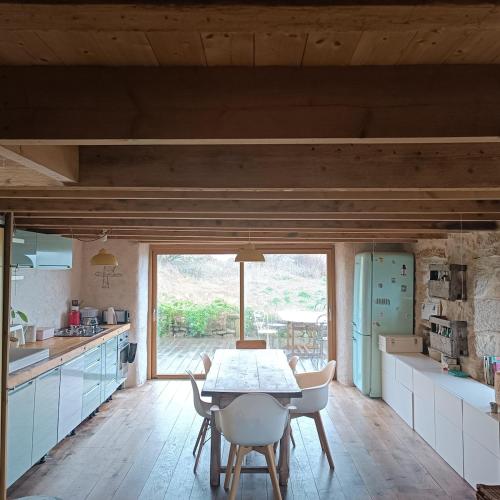 une cuisine avec une table et des chaises et une fenêtre dans l'établissement maison bretonne plage à pied, à Plouhinec