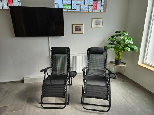 two black chairs in a waiting room with a flat screen tv at Wellness Apartment 