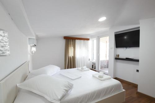 a white bedroom with a bed and a tv at Kashah Residence in Gjirokastër