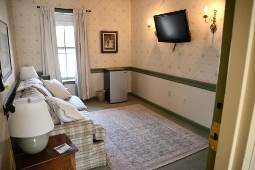 a living room with a couch and a tv on the wall at Strasburg Village Inn in Strasburg