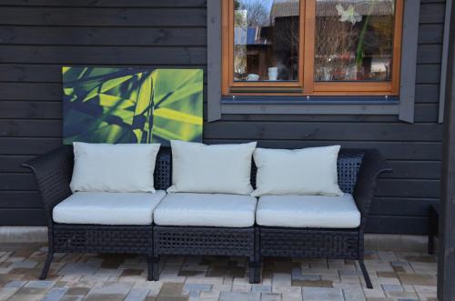 a black wicker couch with white pillows on a patio at Pilava in Roja