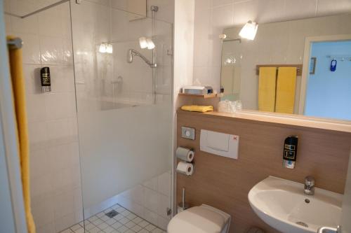 a bathroom with a shower and a toilet and a sink at Hotel Restaurant Am Kellhof in Singen