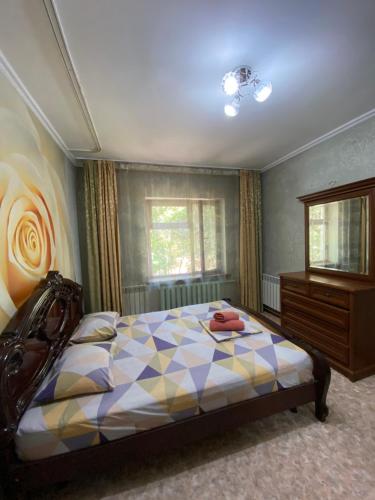 ein Schlafzimmer mit einem Bett und einer Kommode in der Unterkunft Иляева 40 парк Кен Баба in Schymkent