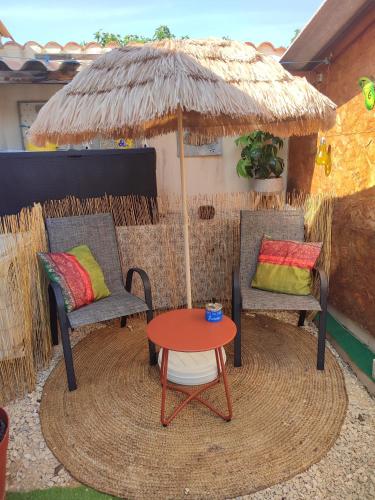 a patio with two chairs and a table and an umbrella at Chez Brigitte Chambre d hôtes avec cour privative,piscine, in Sorgues